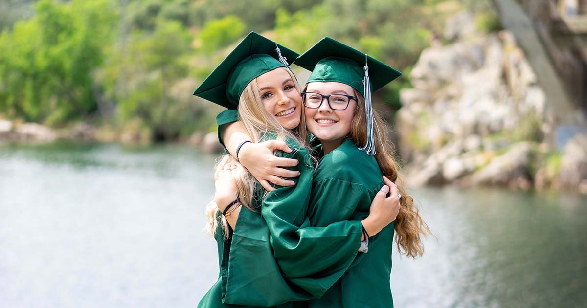 Two college students hugging, smiling at graduation