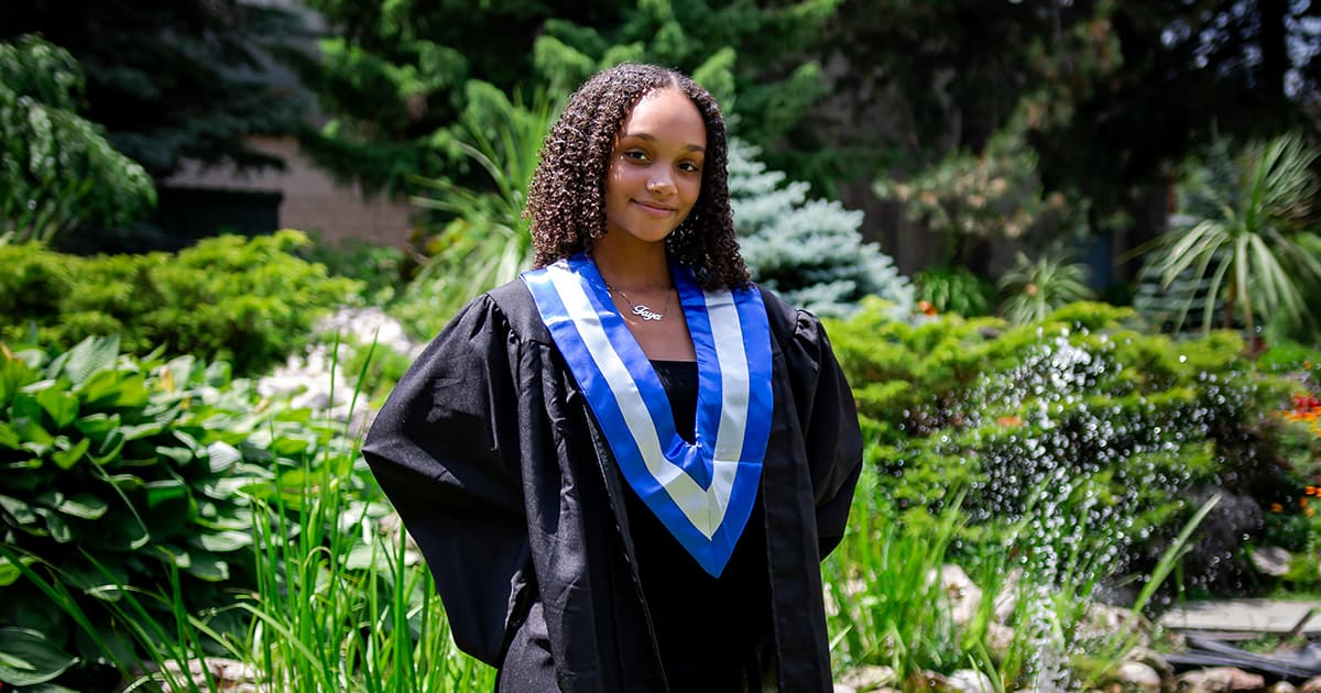 Black female poses in her gown for college graduation